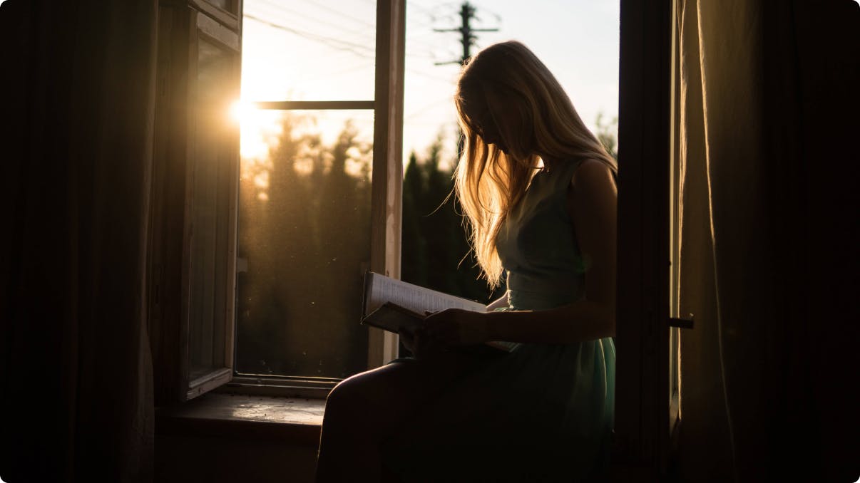 Female reading book under sunset